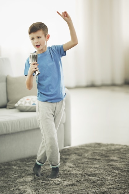 Petit Garçon Chantant Avec Microphone à La Maison