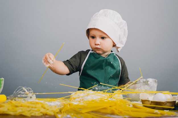 Photo un petit garçon en chapeau de cuisinier prépare le dîner