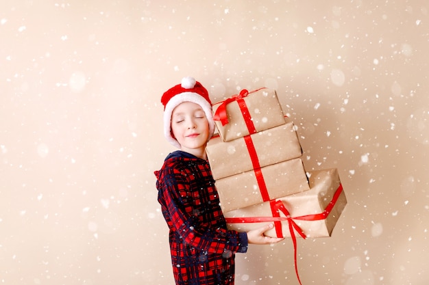 Petit garçon avec chapeau de noël et cadeaux de noël carte de voeux concept de vacances d'hiver