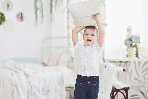 Petit garçon en chemise blanche avec oreiller. Bataille d'oreillers