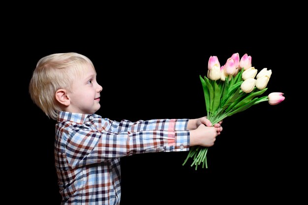 Petit garçon en chemise donne un bouquet de tulipes.