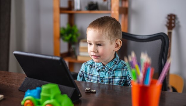 Un petit garçon en chemise regarde l'écran de la tablette