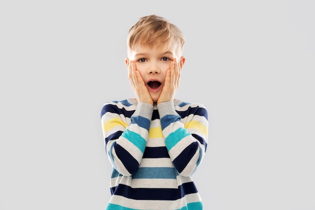 un petit garçon choqué dans un pull à rayures