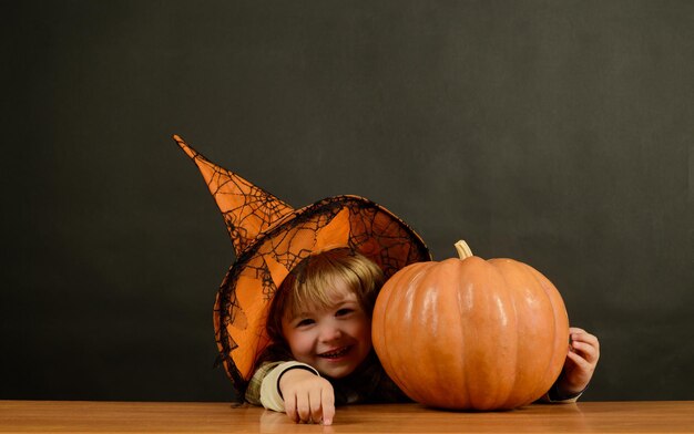 Petit garçon avec citrouille joyeux halloween tout-petit jouant tour ou traiter enfant en chapeau de sorcière se cachant à