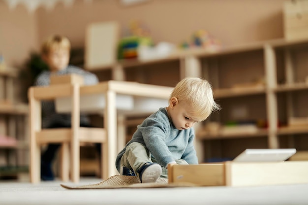 Un petit garçon concentré joue avec un jouet et apprend avec le jeu à la maternelle montessori