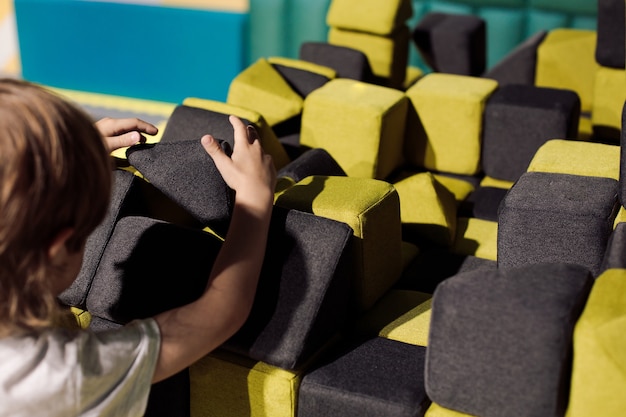 Un petit garçon construit à partir de blocs souples dans un centre scientifique et éducatif pour enfants. Problèmes de communication. Organisation de zones de jeux. Centres de développement pour enfants.