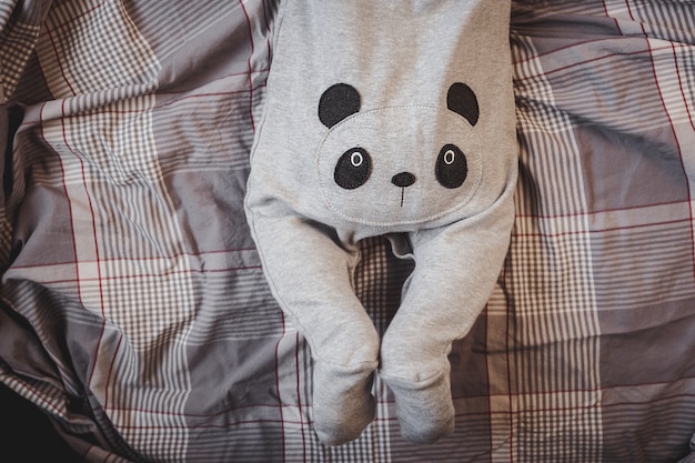 Petit garçon en costume de panda se trouve sur le lit.