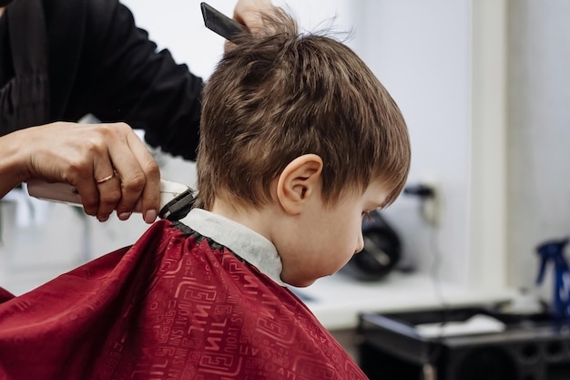 Petit garçon coupé avec la machine du coiffeur