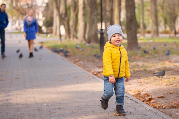 Un petit garçon court le long du chemin dans le parc