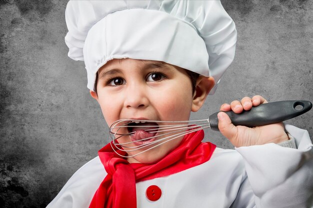 Un petit garçon cuisinier en uniforme sur fond vintage