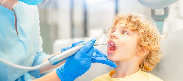 Petit garçon dans un cabinet dentaire, faisant vérifier ses dents par une femme dentiste