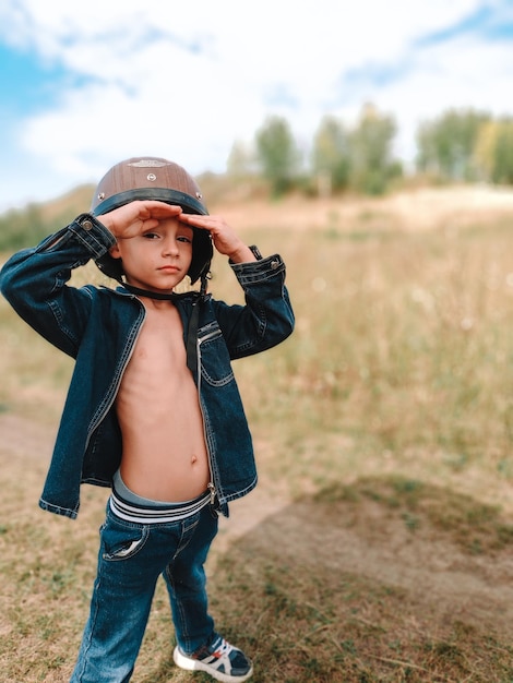 Photo un petit garçon dans un casque de moto marche dans la rue