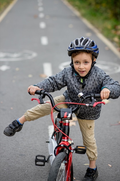 Petit garçon dans un casque à vélo se promène sur une piste cyclable dans le parc.