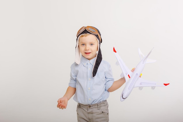 Petit garçon dans un chapeau de pilote et avec un avion sur fond blanc