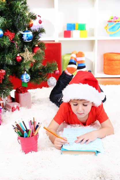 Le Petit Garçon Dans Le Chapeau De Santa écrit La Lettre Au Père Noël