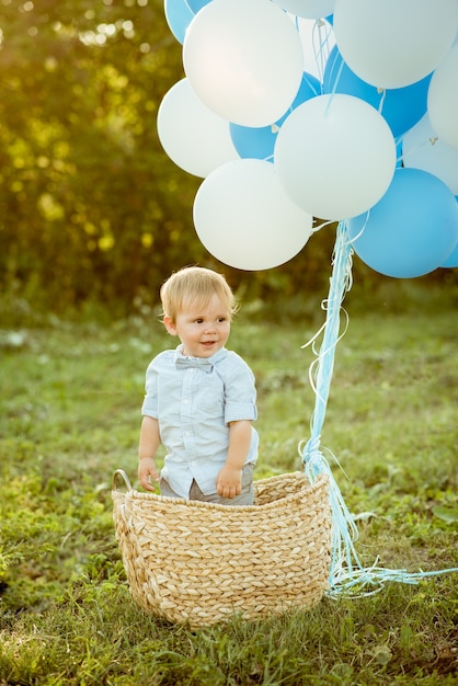 Petit garçon dans un panier en osier avec des ballons