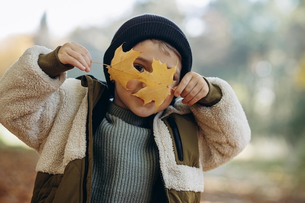 Petit garçon dans le parc tenant des feuilles d'automne