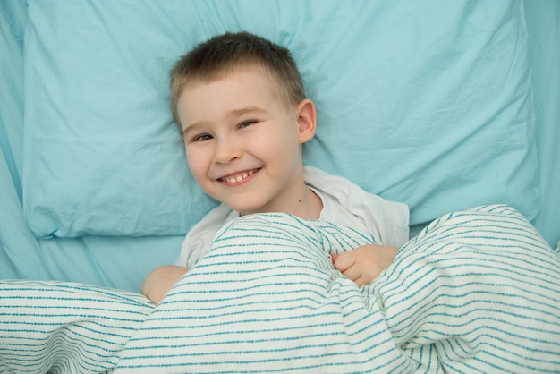 Petit garçon dans son lit sourit avant de dormir