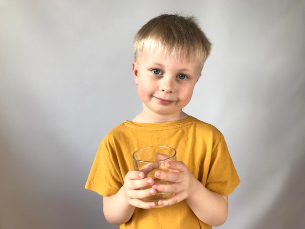 petit garçon dans un t-shirt jaune boit de l'eau