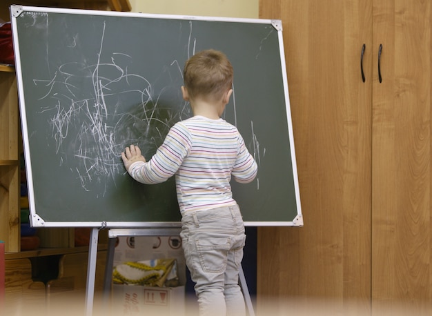 Petit garçon dessin sur un tableau au jardin d&#39;enfants