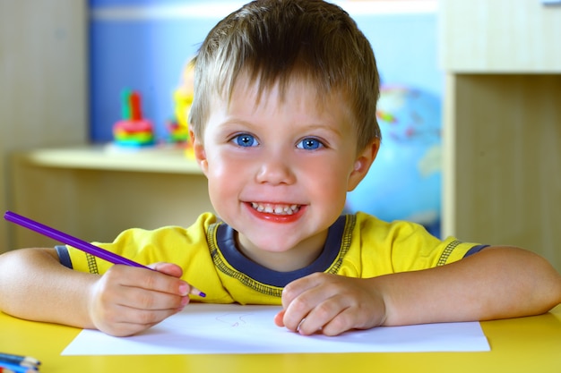 Petit garçon dessine avec des crayons de couleur