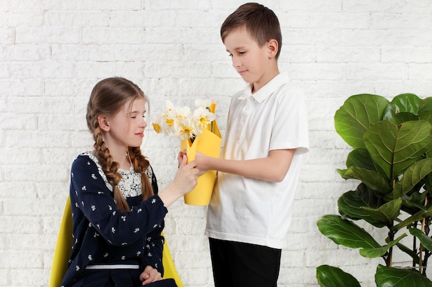 Le petit garçon donne des fleurs à la petite fille