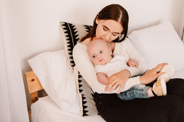 Petit garçon drôle bébé enfant mignon, la mère tient l'enfant, allongé sur le lit, berçant l'enfant