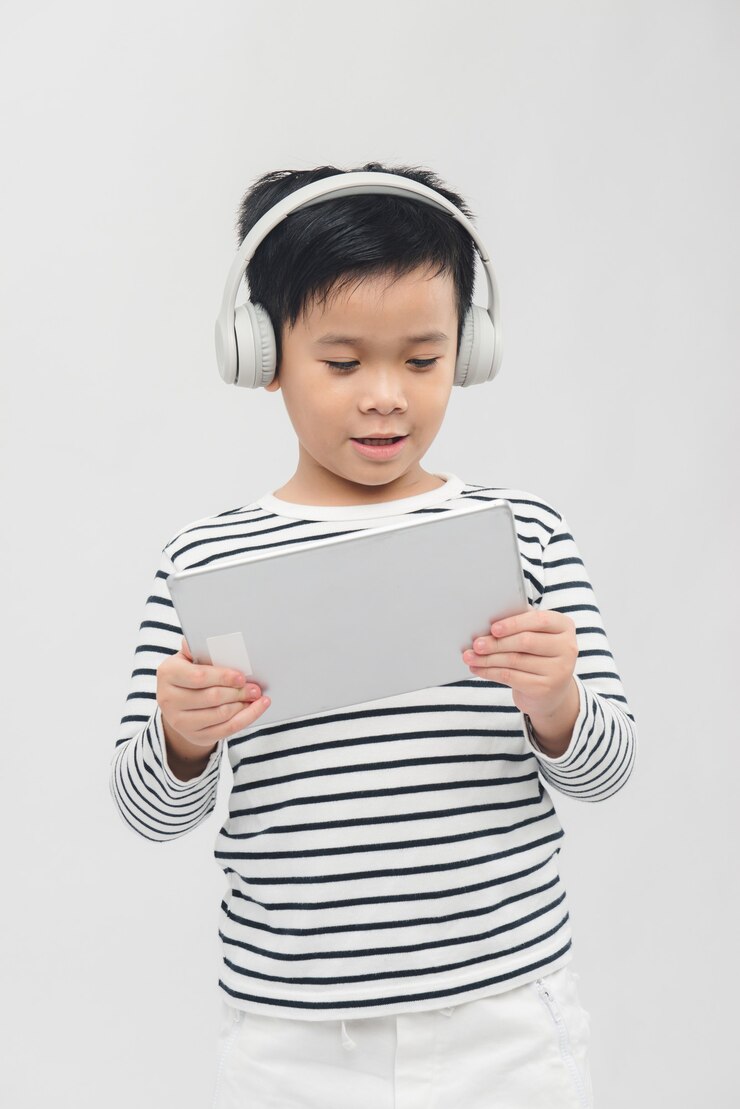 Photo petit garçon écoutant de la musique depuis sa tablette sur ses écouteurs.