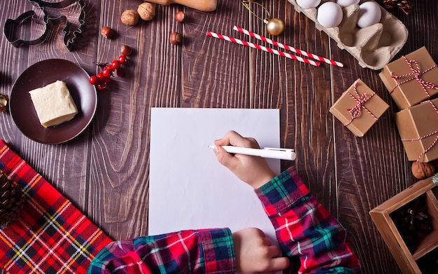 Petit garçon écrit une lettre au Père Noël à Noël