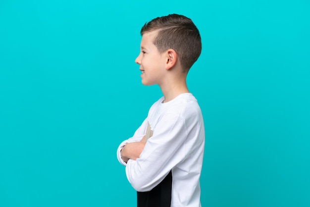 Petit garçon enfant isolé sur fond bleu en position latérale