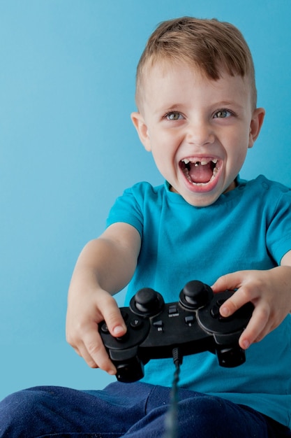 Petit garçon enfant portant des vêtements bleus tenir dans la main joystick pour le jeu
