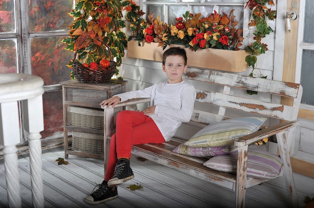 Un petit garçon est assis sur une chaise dans le jardin en automne