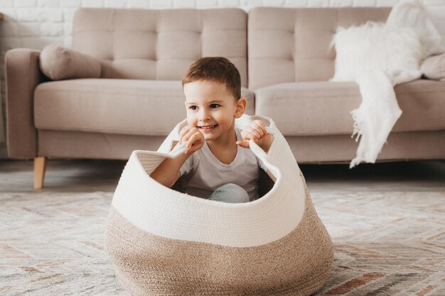 Un petit garçon est assis dans un panier en osier et rit Concept d'enfance heureuse