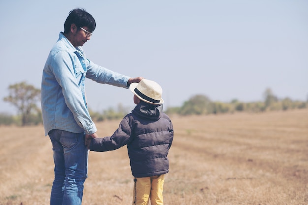 Petit garçon est assis sur les épaules de son père dans le champ