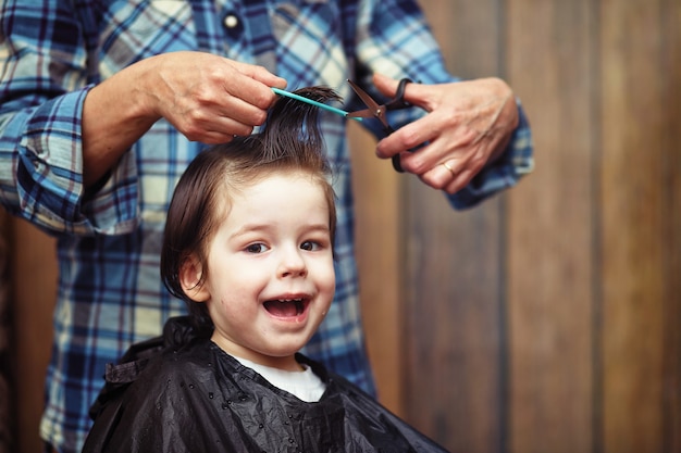 Un petit garçon est taillé dans les émotions vives du coiffeur sur son visage