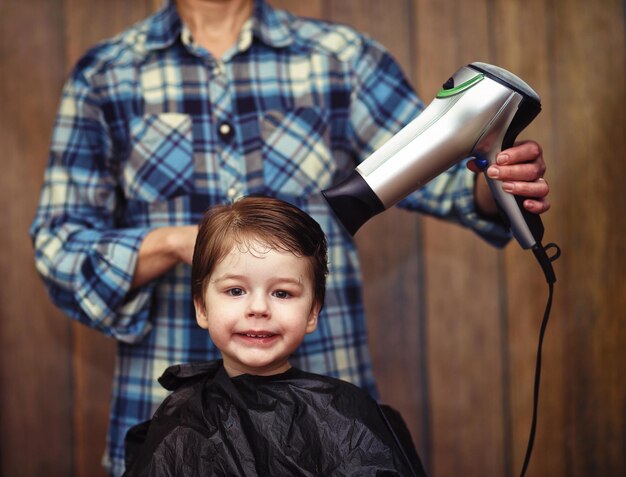 Photo un petit garçon est taillé dans les émotions vives du coiffeur sur son visage