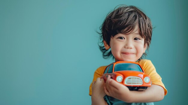Un petit garçon étreint un jouet de voiture sur un fond bleu pastel