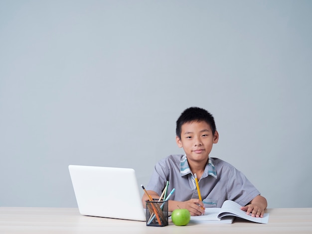 Petit garçon étudiant en ligne avec un ordinateur portable. Enseignement à distance pendant la pandémie COVID-19