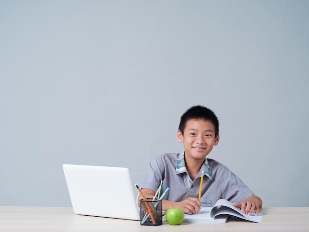 Petit garçon étudiant en ligne avec un ordinateur portable. Enseignement à distance pendant la pandémie COVID-19