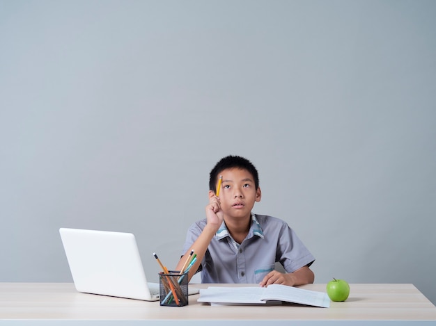 Petit garçon étudiant en ligne avec un ordinateur portable. Enseignement à distance pendant la pandémie COVID-19