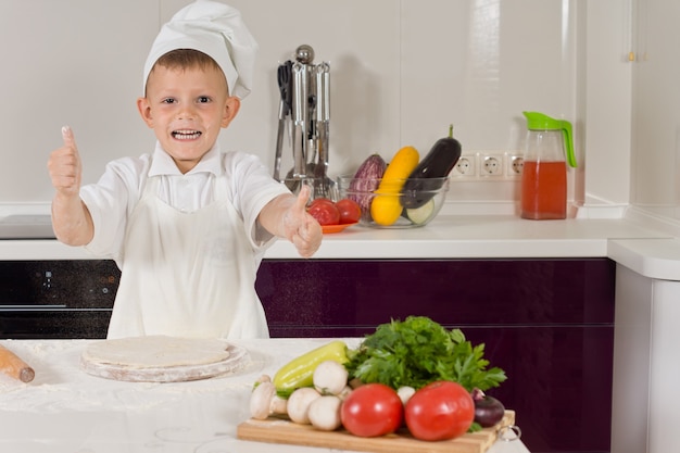 Petit garçon excité cuisine pizza faisant un coup de pouce