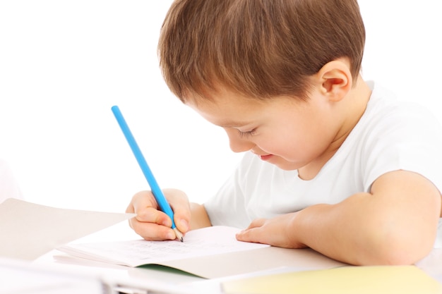 Un petit garçon à faire ses devoirs sur fond blanc