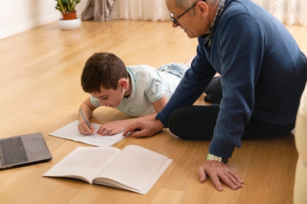 Petit garçon à faire ses devoirs avec son grand-père à la maison