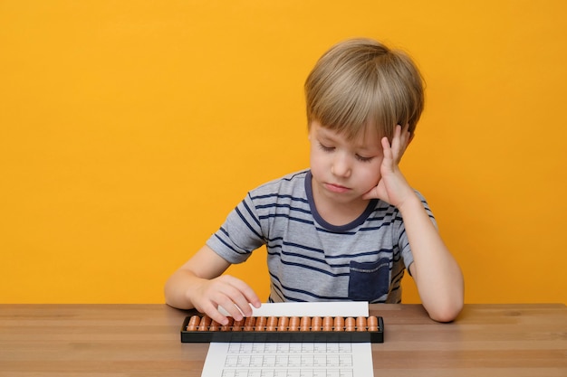 Petit garçon faisant des exercices mathématiques simples avec des scores de boulier.