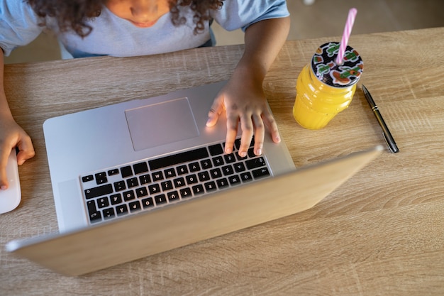 Le petit garçon fait ses devoirs à la maison avec l'ordinateur