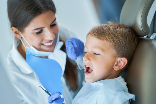 Petit garçon et femme dentiste dans le bureau des dentistes