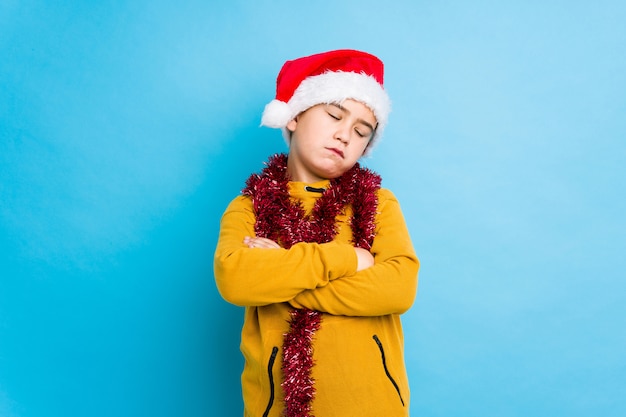 Petit garçon fête le jour de Noël portant un bonnet de Noel isolé fatigué d'une tâche répétitive.