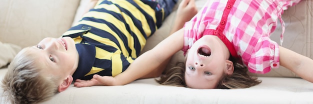 Petit garçon et fille allongée sur le canapé à l'envers à la maison