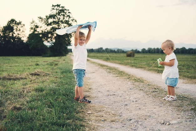 Petit garçon et fille avec cerf-volant sur la nature à la campagne Famille à l'extérieur Enfants jouant sur le pré au coucher du soleil Photo de loisirs rêves vacances d'été valeurs familiales mode de vie durable