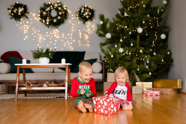 Petit garçon et une fille en pyjama confortable et chapeaux de père Noël